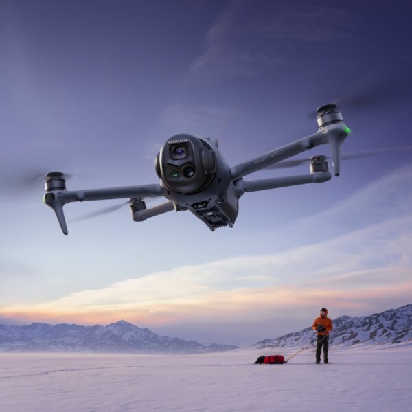 DJI Mavic 4 Pro dron u letu iznad snežne ravnice sa pilotom u pozadini
